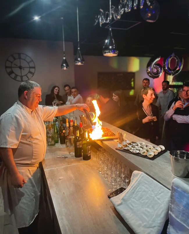 Chef réalisant une animation culinaire flambée devant les invités lors d'une soirée d'entreprise aux Rois Maj