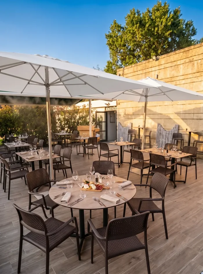 Tables dressées sous les parasols sur la terrasse des Rois Maj à Meyreuil
